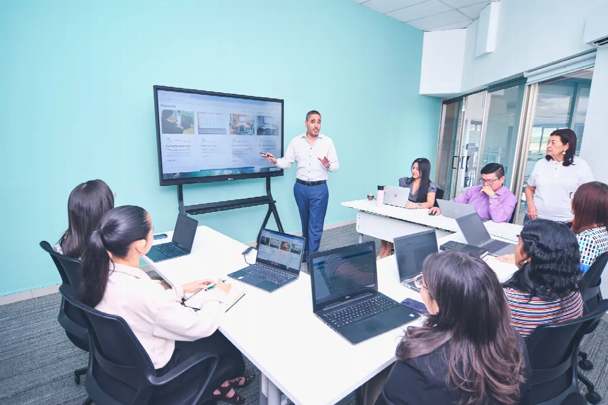 Collaborateurs formés autour d'ordinateurs en entreprise